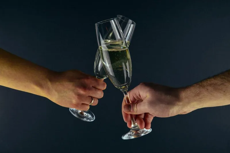 Two guests touching champagne glasses at a black-tie gala