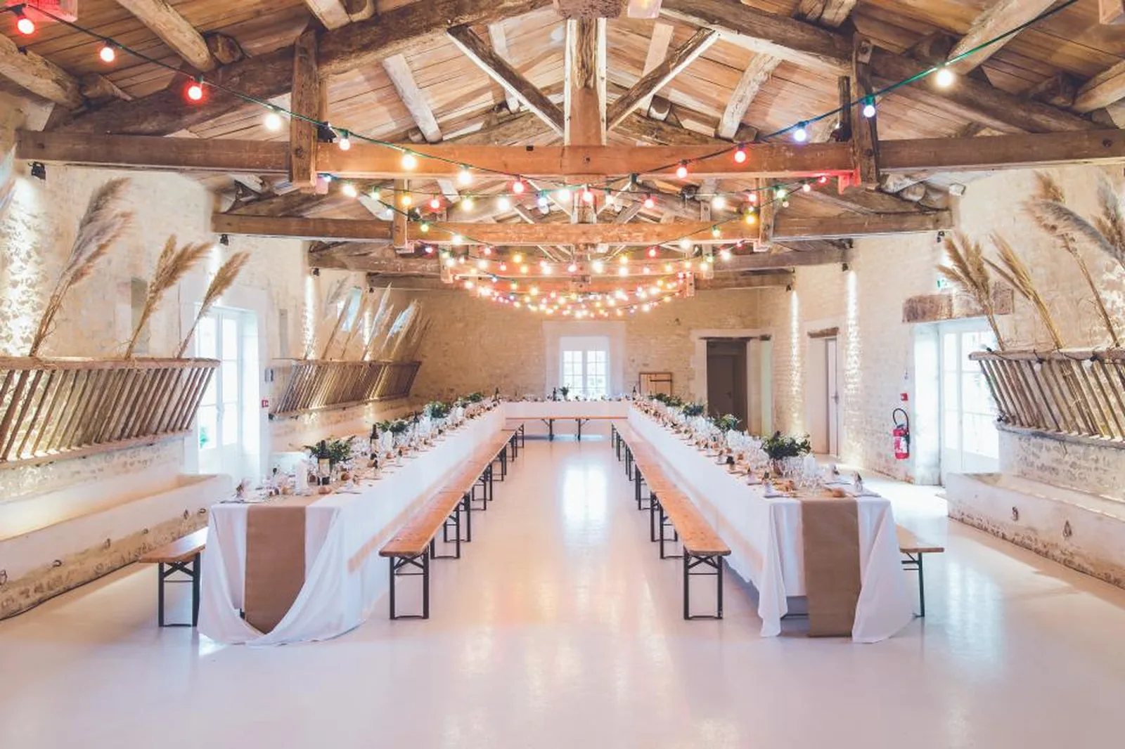 Long banquet tables set for a reception in a timber-beamed hall
